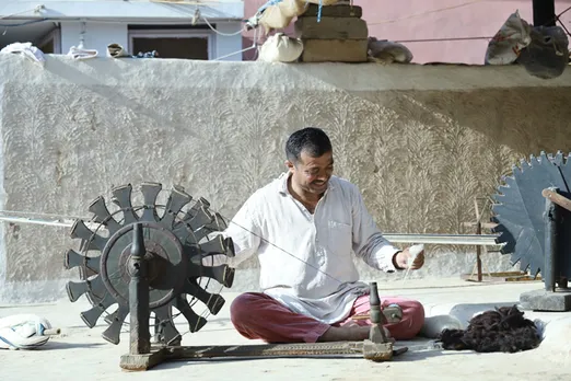 The process starts with spinning the raw wool fibres or cotton on the traditional wooden wheel (charkha) to make yarn.  Shamji Valji still uses the traditional wooden charkha (spinning wheel) even now.  Pic: Shamji Valji  30 stades